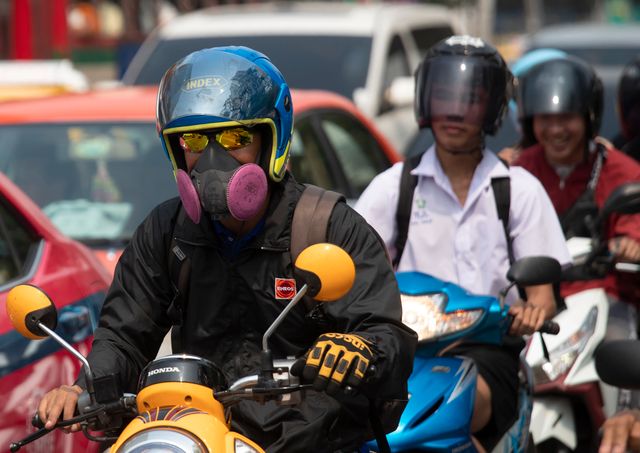 Mc-förare med andningsskydd i Bangkok-trafiken.