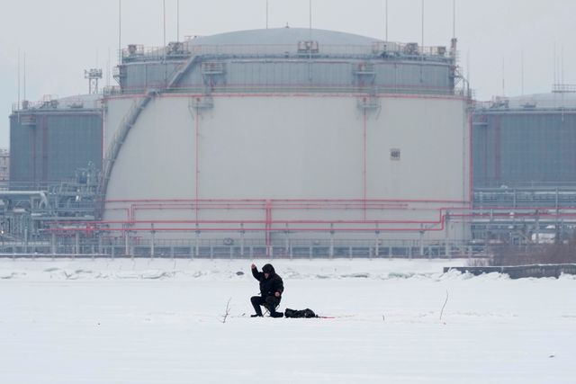 En ensam fiskare framför en oljecistern utanför S:t Petersburgs hamn. Arkivbild.