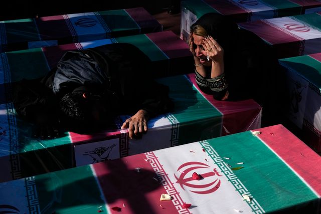 Sörjande vid en kista draperad med en flagga efter explosionen i onsdags, under en ceremoni i staden Kerman under fredagen.