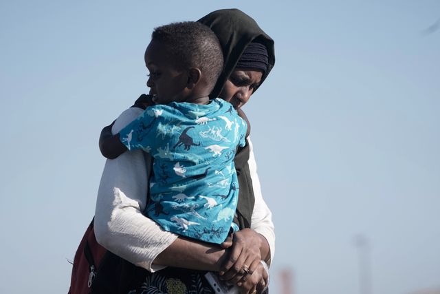 En sudanesisk kvinna på flykt bär sin son