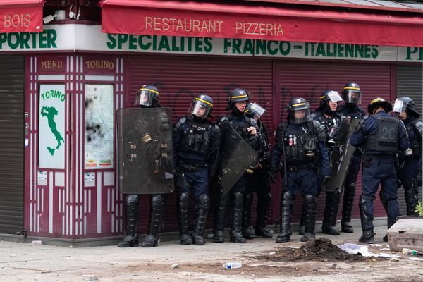 Kravallpolis tar skydd bakom en restaurang under protesterna i Paris.