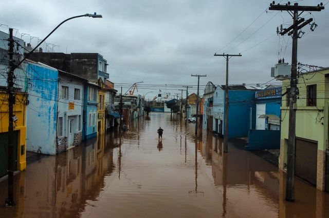 En man vadar fram i översvämningarnas Porto Alegre.
