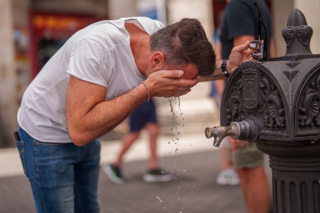 En man svalkar sig i en fontän i Madrid i den 40-åriga värmen.