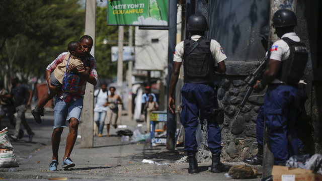 En pappa springer undan en polisinsats mot gängbrottslingar i Port-au-Prince.