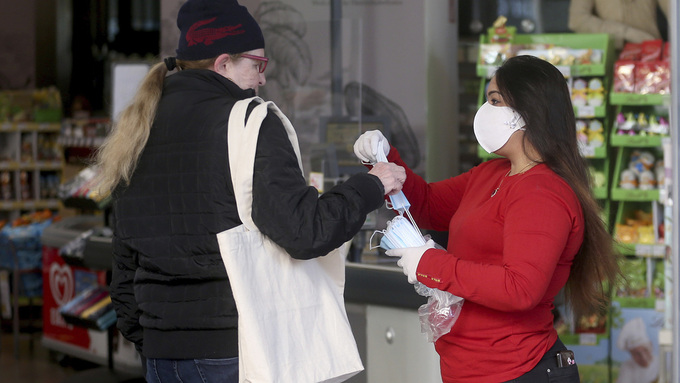 Ansatte ved et supermarked i Wien deler ut ansiktsbeskyttelse til kundene.