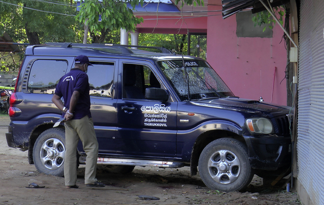 En politimann inspiserer kulehull i en bil etter skytingen på en politistasjon på Sri Lanka 1. juledag.