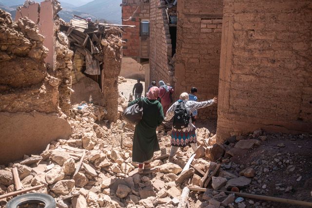 Människor går bland rasmassorna i byn Moulay Brahim, som ligger nära jordbävningens epicentrum.