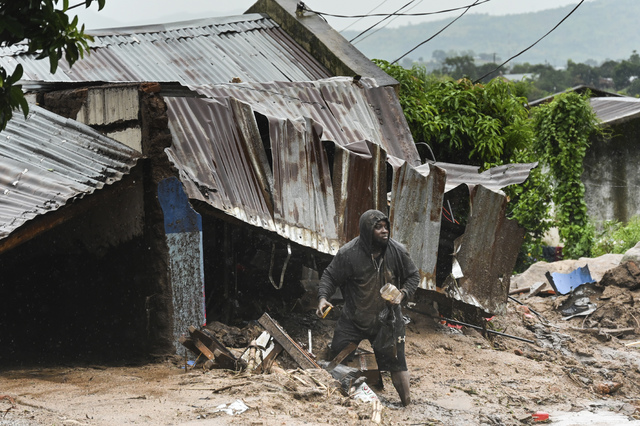 En man står utanför sitt raserade hus i Blantyre i Malawi.