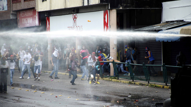 <p><b>DEMONSTRASJONER I FLERE BYER:</b> Dette bildet viser sammenstøt mellom støttespillere av opposisjonen og politet i San Cristobal i Venezuela 19. april. Politiet bruker blant annet vannkanoner for å temme folkemassene. </p>