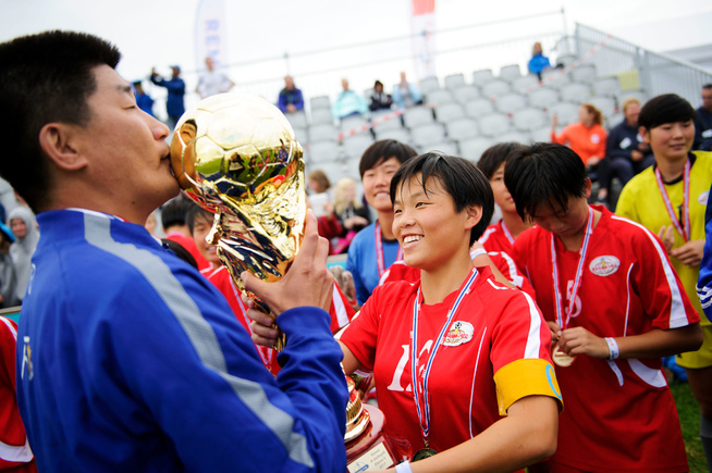 <p/> <p>Trener Jang Kyong Il kysser pokalen mens deres lagkaptein Hong Song Ok holder den. Jentene bryter ut i latter idet det skjer. </p>