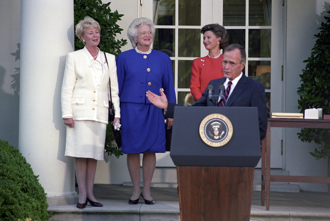 <p>FORAN DET HVITE HUS: USAs president i 1991, George H.W. Bush holder en tale. Bak ham i rødt står dronning Sonja.</p>
