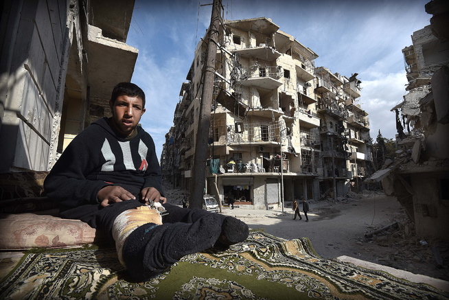 <p>SKADER I BEINA: Muhamed Assaf (22) sitter på restene av en delvis ødelagt balkong, med utsikt mot ødelagte nabobygg. Han har skader i begge beina etter bombardementet i Øst-Aleppo.</p>
